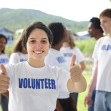 happy volunteer girl showing thumbs up sign, group in background