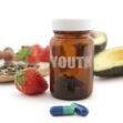 Anti-aging pills surrounded by nutritious superfoods including avocado, pumpkin seeds and berries