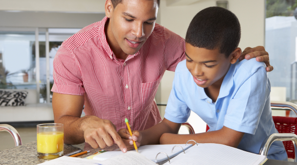 Father Helping Son With Homework In Kitchen