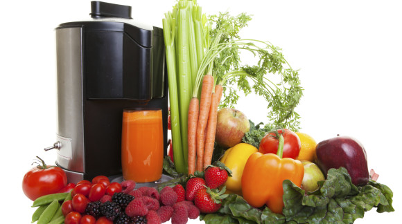 A Juicer surrounded by healthy fruits and vegetables, isolated on white.