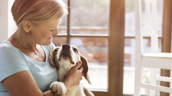 Senior woman with her dog inside of her house.