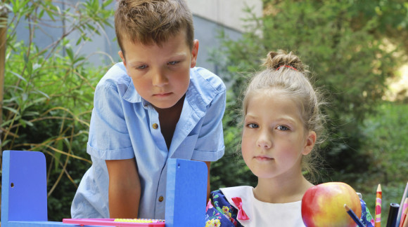 Stylish boy and girl playng school outside. Education and kids fashion concept