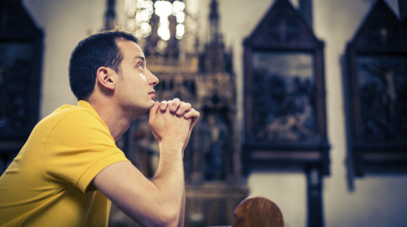 Handsome young man praying in a church