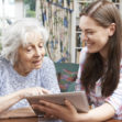 Teenage Granddaughter Showing Grandmother How To Use Digital Tablet