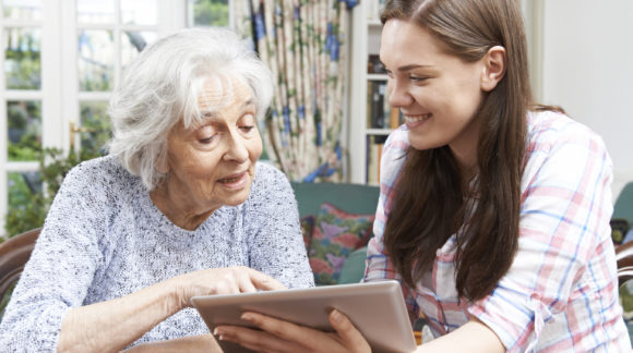 Teenage Granddaughter Showing Grandmother How To Use Digital Tablet