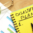 Notepad with disaster plan on a wooden table.