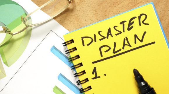 Notepad with disaster plan on a wooden table.