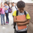 Pupils friends teasing a pupil alone in elementary school